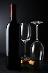 Elegant red wine glass and a wine bottle in black background