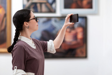 Cultural education and modern exhibition in gallery. Side view of woman visiting excursion in...