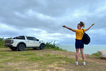 portrait young beautiful girl travels, hiking, walking with a backpack in the mountains view on islands, smiling. Woman traveller is driving a car, road trip. Carefree, hands up