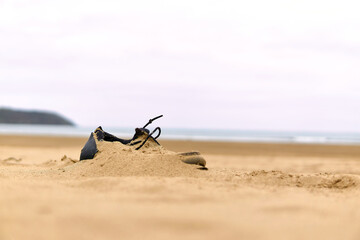 A lost shoe on the beach, covered by sand blown by the wind