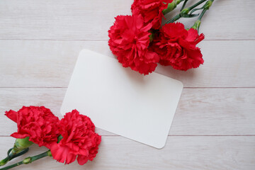 Red Carnation decoration with blank greeting card on wooden background. floral background for Mother's day, Women's day and Valentine's day. 