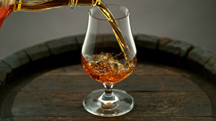 Pouring cognac into the glass, macro shot.