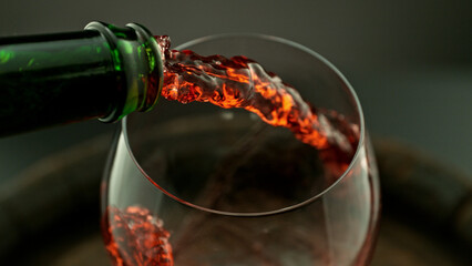 Pouring red wine into the glass, macro shot.