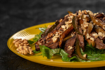 beef salad with vegetables and walnut on black background