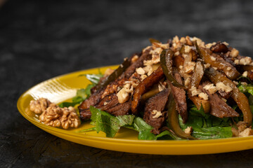 beef salad with vegetables and walnut on black background