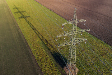 Power supply pole on farmland with powerlines and cables