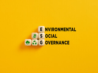 The acronym ESG and Environmental Social Governance text on wooden cubes on yellow background.