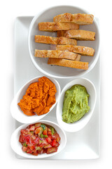 Entrante con pan, guacamole, Pimiento y pico de gallo sobre una loza blanca y fondo blanco