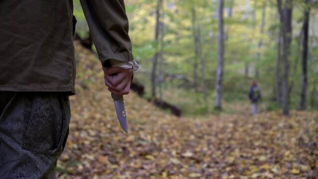 A maniac with a knife is chasing a victim in the forest. Man killer crazy attacks woman in the forest