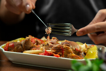 man eats lamb stew on the bone with vegetables. Khashlama is popular Armenian dish, which is prepared from beef with vegetables. Khashlama in the plate.  caucasian food