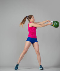 Naklejka premium Training with kettlebells, a young athlete performs exercises with kettlebells, kettlebell lifting for the tone of the whole body