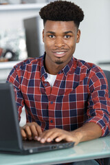 funny student man sitting at table with laptop