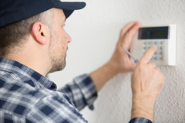 male contractor programming electronic keypad on the wall