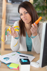 unconvinced woman holding carrot and tape-measure