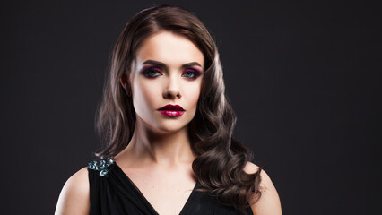 Gorgeous young brunette in a chic evening look. Scarlet lips and eye shadow, wave hair styling