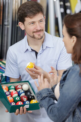 retailer showing customer a box of pool balls