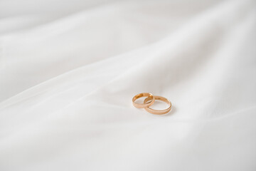 golden wedding rings lie on the bride's white veil