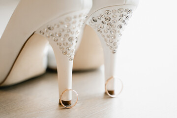 Obraz na płótnie Canvas gold wedding rings at the heels of the bride's shoes