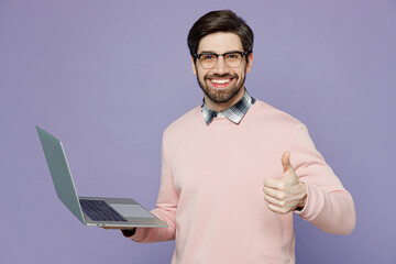 Young smiling happy fun caucasian IT man he wear casual clothes pink sweater glasses hold use work...