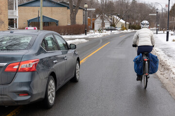 Cycliste roulant dans la rue en hiver et auto qui contourne