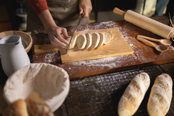 Fototapeta na wymiar Top view of baker Using knife to cut Baguette on kitchen table