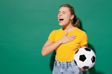 Side view young woman fan in basic yellow t-shirt cheer up support football sport team hold soccer...