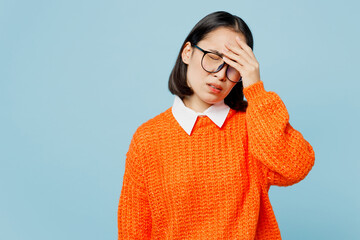 Young sad woman of Asian ethnicity wear orange sweater glasses put hand on face facepalm epic fail...
