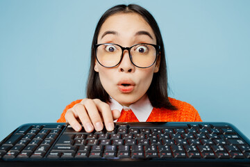 Young nerd smart IT woman of Asian ethnicity wear orange sweater glasses typing on close up pc...