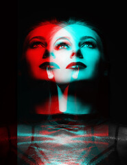 Studio portrait of beautiful woman with fancy evening make-up in red and blue color split effect. Model looking up in black studio background. Woman wearing silver blouse. Futuristic looking style