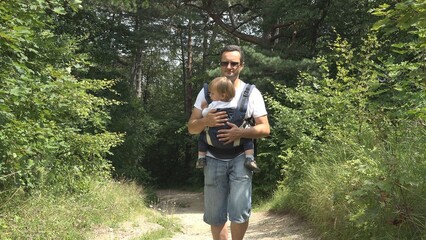 Father holding baby hiking on mountain path