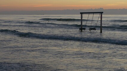 Fototapeta na wymiar Empty wooden swing above sea water, romantic sunset
