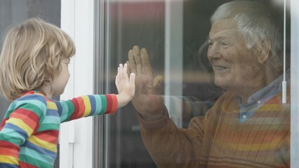 Little child put hand on window to touch grandparent hands, window barrier, safe