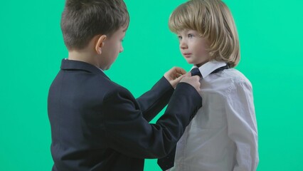 Bigger child arrange youngest brother tie, learning in family, green screen back