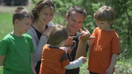 Father captured a snake, mother and children looking at dangerous animal, green