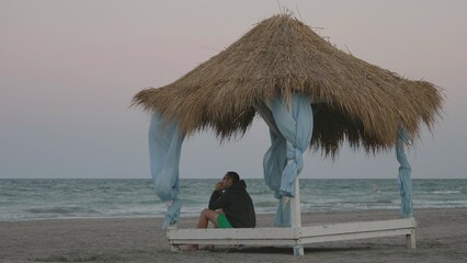 thoughtful man sit in reed canopy on empty beach, wind and cold, restless sea © MEDIAIMAG
