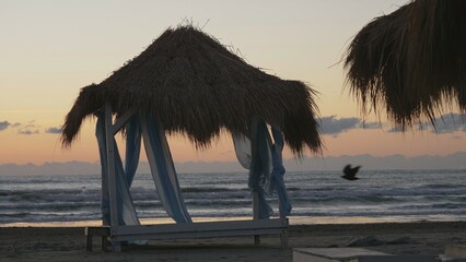 Beach straw canopy silhouette on colorful sunrise skyline