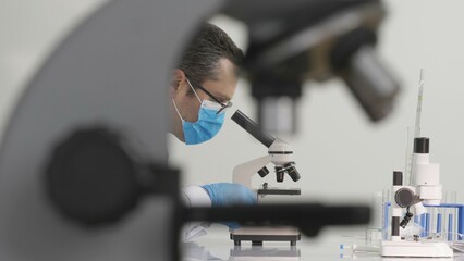 Biochemist working in the lab behind microscope