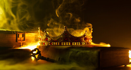 Obraz premium A golden crown, an old book, a key and old casket on a dark background. Panoramic view of the fog. Layout for your logo. A horizontal banner with a place to copy the cover image of a popular website.