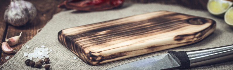 Cutting board on a wooden table with spices. Handmade chopping board. Fresh vegetables and cutting board