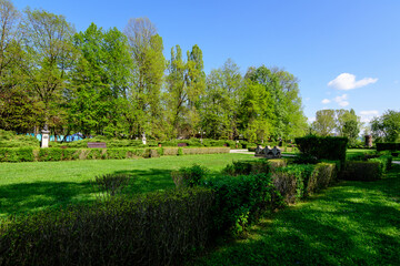 Landscape with vivid green trees and grass in Chindia Park (Parcul Chindia) from Targoviste city in Romania in a sunny spring  day with white clouds and blue sky