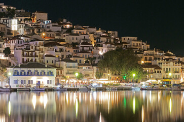 Fototapeta na wymiar Skopelos harbor night lights mirrored in the Mediterranean Sea