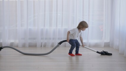 Funny little child learn to use vacuum cleaner, young help, early responsibility