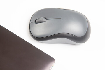 Computer wireless mouse next to a laptop on a white table close-up. electronic personal industry