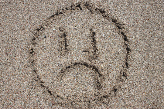 sad emoticon on beach sand