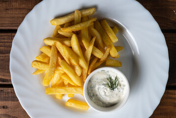 French fries on a white plate on a wooden table