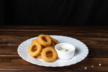 Onion rings in breadcrumbs on a white plate
