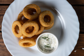 Onion rings in breadcrumbs on a white plate