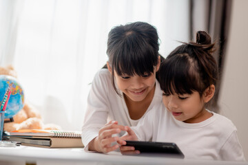 Concept kids and gadgets. Two little girls siblings sisters look at the phone and smile. They hold a smartphone watch videos, learn, play games, speak online. Internet for children. Parental control
