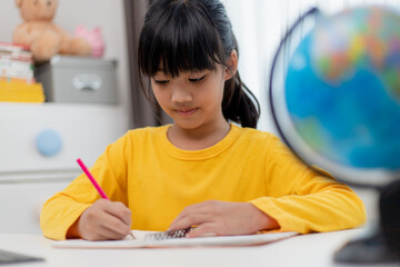 Asian schoolgirl doing her homework with digital tablet at home. Children use gadgets to study. Education and distance learning for kids. Homeschooling during quarantine. Stay at home