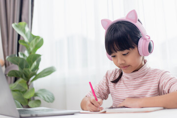 Asian little girl in headphones have video call distant class with teacher using laptop, study online on computer, homeschooling concept